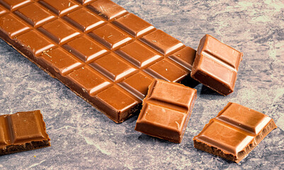 Milk Chocolate Bar with Broken Pieces on Stone Surface