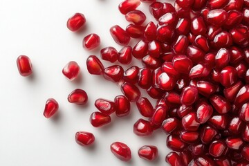 Fresh pomegranate seeds scattered on a white surface showcasing their vibrant red color and glossy appearance