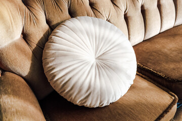 Cozy round cushion on elegant tan couch in a well-lit living room setting