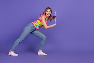 Happy young woman in casual outfit posing playfully against a bright purple background for lifestyle and fashion concepts