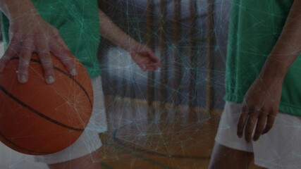 Two female teammates dribbling basketball on gym court, featuring sports analytics network overlay - Powered by Adobe