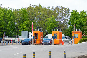 Toll parking entrance booths outside on a street with convoy of cars waiting to get in