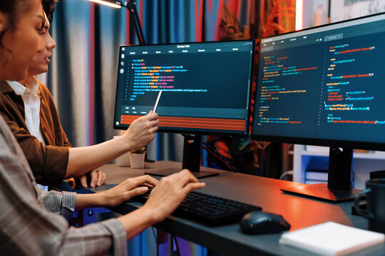 IT developers discussing with point to intelligent website development coder system running data online two screens information technology at neon light room at modern office. Infobahn.