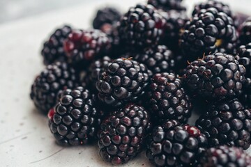 Fresh ripe blackberries mulberry close-up on light background. Macro shot of juicy blackberries piled together, showcasing their deep color and texture on a bright neutral surface