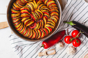 Homemade ratatouille preparation and serving. Child's hands placing vegetable slices into a baking...