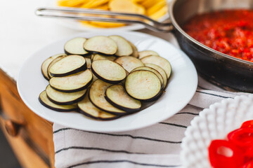 Homemade ratatouille preparation and serving. Child's hands placing vegetable slices into a baking dish. Fresh ingredients, vintage cutlery, cozy kitchen scene, flat lay and side views