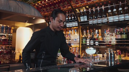 Fototapeta premium Asian bartender serving mixed creamy vodka cocktail glass adding pink flower top with sugar burned on ice at front making special drink, focusing alcohol refreshing at luxurious counter bar. Vinosity.