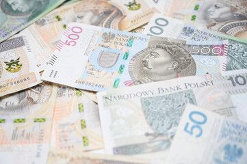 Flat lay of colorful Polish zloty banknotes spread out on a clean white table. Ideal image for topics related to economy, currency exchange, inflation or Poland’s financial market.