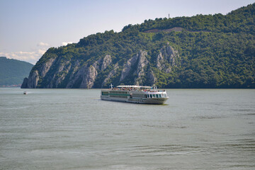 River Cruise Ship on the Danube with Rocky Cliffs and Greenery