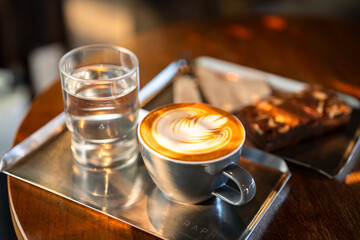 Hot coffee latte with latte art milk foam in cup mug and Homemade Brownie on wood desk on top view. As breakfast In a coffee shop at the cafe,during business work concept,vintage style