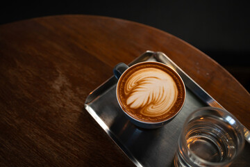 Hot coffee latte with latte art milk foam in cup mug on wood desk on top view. As breakfast In a coffee shop at the cafe,during business work concept,vintage style