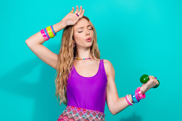 Charming young woman in retro fashion lifting a dumbbell on a turquoise background conveying exercise, fun, and vintage flair