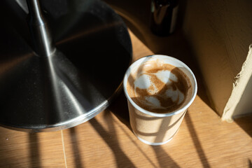 Hot coffee latte with latte art milk foam in cup made of paper on wood desk on top view. As breakfast In a coffee shop at the cafe,during business work concept,vintage style