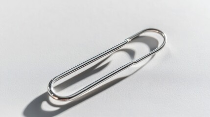 Silver paperclip on white background minimalist office stationery image