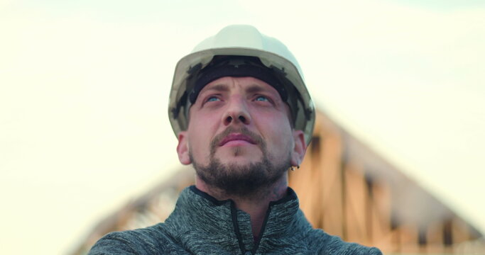 Construction worker in hard hat looking upward confidently, open structure in background, symbolizing vision, pride, and commitment to construction excellence