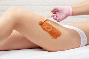 The beautician makes a cosmetic peeling procedure on the thighs of a woman. Spa procedures in a beauty salon.