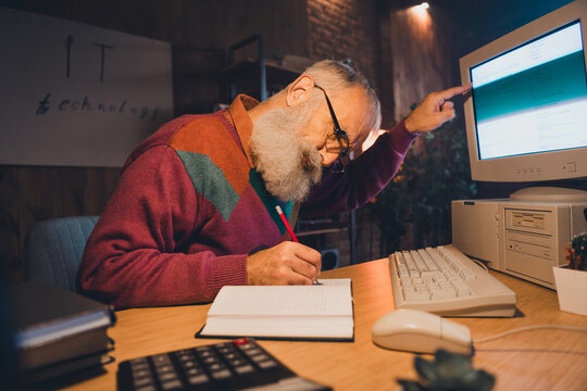 Elderly male professional working on a computer in an office environment highlighting IT, technology, and education skills