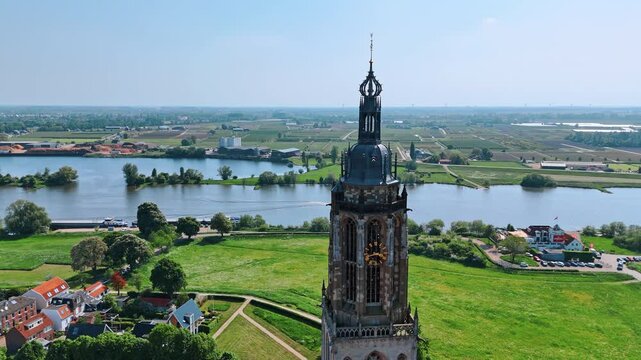Flight around the top of Church in Rhenen, the Netherlands. View on the beautiful nature, cityscape of the municipality and river on sunny daytime.