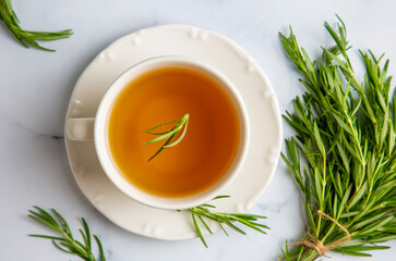 Cup of healthy rosemary tea with fresh rosemary bunch on rustic background, winter herbal hot drink concept, salvia rosmarinus
