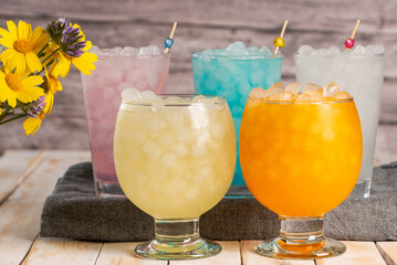 Several glasses with ice and soda of various flavors and colors, close-up.