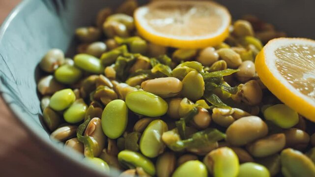 Close up view of colorful beans and chopped greens in a bowl with fresh lemon slices, a healthy and vibrant vegetarian dish