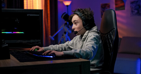 A smiling child gamer beats a round in an online game, claps in delight, and jokes with teammates...