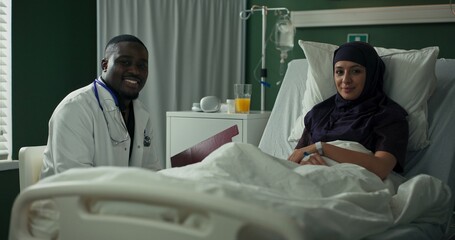 Doctor walks in with encouraging news, engaging with patient through detailed charts on tablet.
