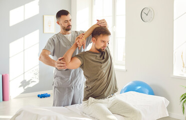 Therapist performing massage and stretching arm joints exercises to aid in the patient recovery. This physiotherapy and rehabilitation session improving joint mobility and promote medical healing.