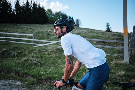 Cyclist in white jersey rides road bike on scenic mountain road.  Stunning landscape backdrop. Active lifestyle and sports photography. - Powered by Adobe