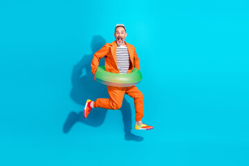 Cheerful man in bright orange suit posing with inflatable ring against a vibrant blue background showcasing fun and style