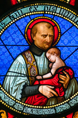 Stained glass (19th century) of St. Vincent de Paul carrying a child in his arms. Saint of the...