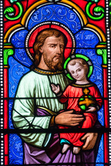 Stained glass (19th century) of Saint Joseph holding baby Jesus Christ in his arms.