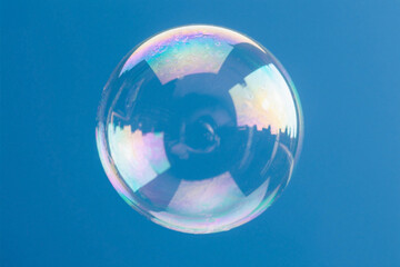 Abstract soap bubble floating on a blue background with clear glass texture and pastel hues. Light, airy, and dreamy visual ideal for design, backgrounds, and creative projects.

