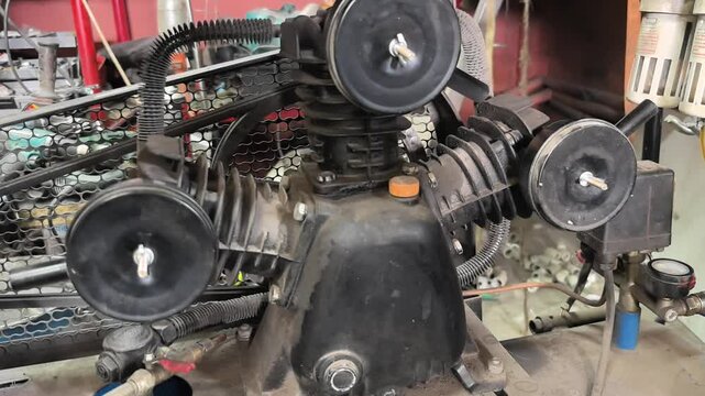 This clip highlights crucial maintenance being performed on a small air compressor in a garage, showcasing the engine's condition and key components for efficient operation.