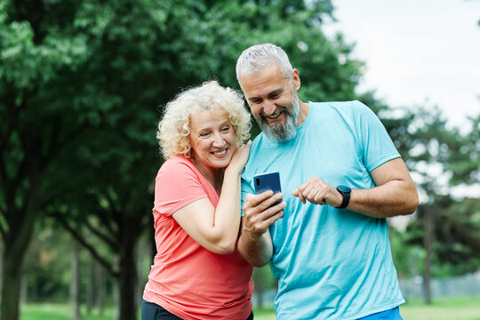 man woman outdoor retirement couple phone mobile smartphone  mid adult middle age middle aged mature active park old using internet smart phone mature cell performance app