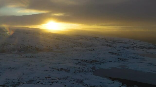 Drone captures the sun rising over Iqaluit's snow-covered terrain, illuminating the Arctic landscape with warm hues amidst the cold environment.