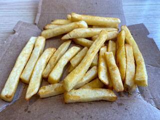 Freshly cooked fries from the oven rest on a paper box