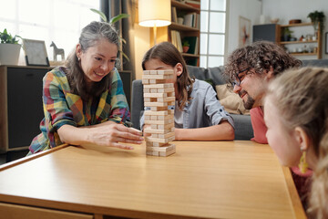 Happy family spending quality time together playing Jenga at home, engaging in fun activity. Living...
