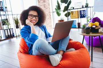 Young professional woman in modern workspace using a laptop in a casual and stylish setting with a vibrant atmosphere