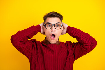 Surprised Handsome Young Man in Red Sweater Expressing Shock Against Yellow Background