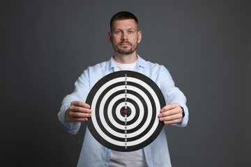 Targeting. Man with dart board on grey background