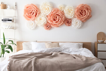 Beautiful decorative paper flowers on wall in bedroom