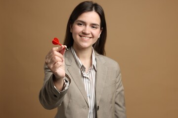Targeting. Smiling businesswoman with dart on beige background, selective focus