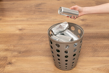A hand places an aluminum can into a recycling bin, emphasizing the importance of separating waste....