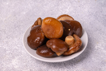 salted mushrooms lie on a white plate, on a white background, copy space