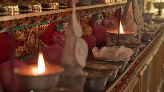 Oil Candles burning on a shelf with religious decorations in buddhist monstery