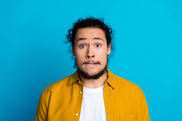 Fototapeta premium Portrait of a trendy man with a surprised expression, wearing a yellow shirt, set against a bright blue background