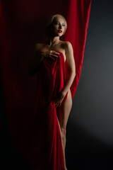 Elegant woman posing with red cloth in a studio setting