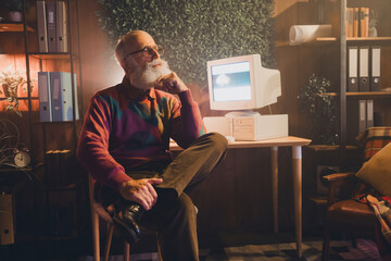Elderly male programmer working on retro computer in cozy home office with warm lighting,...