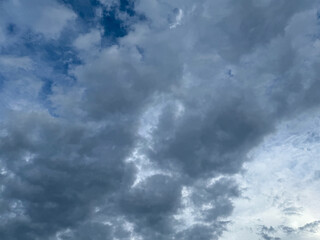 Stormy sky with dark, snowy clouds on a spring day. Clouds are floating across the sky. Dramatic clouds. Dark blue clouds swiftly floating across blue sky. Sky texture, abstract nature background.